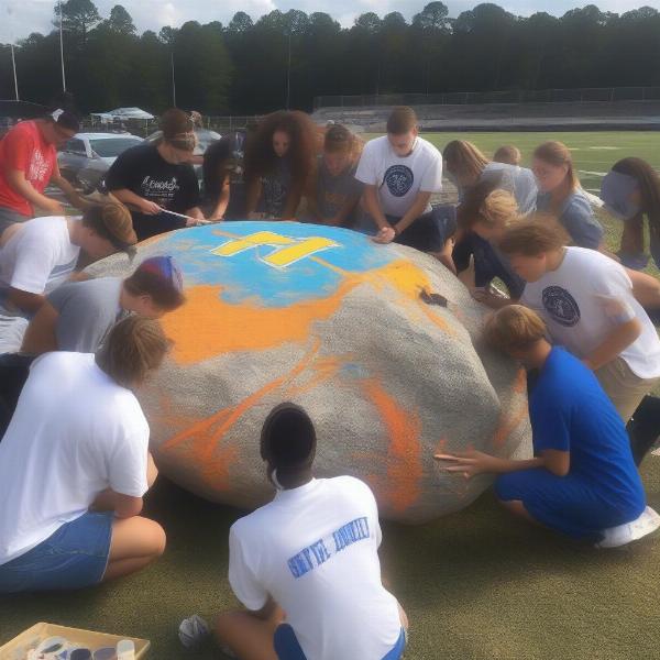 Students painting The Rock with school colors and mascot for football game
