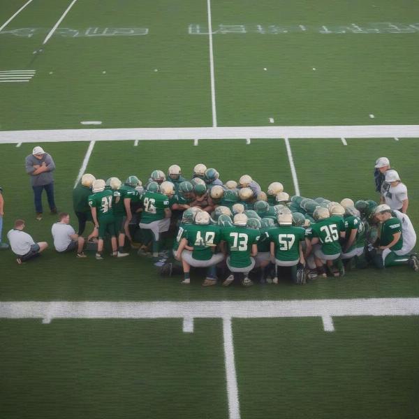 East Grand Rapids football team in a huddle on the field during a game